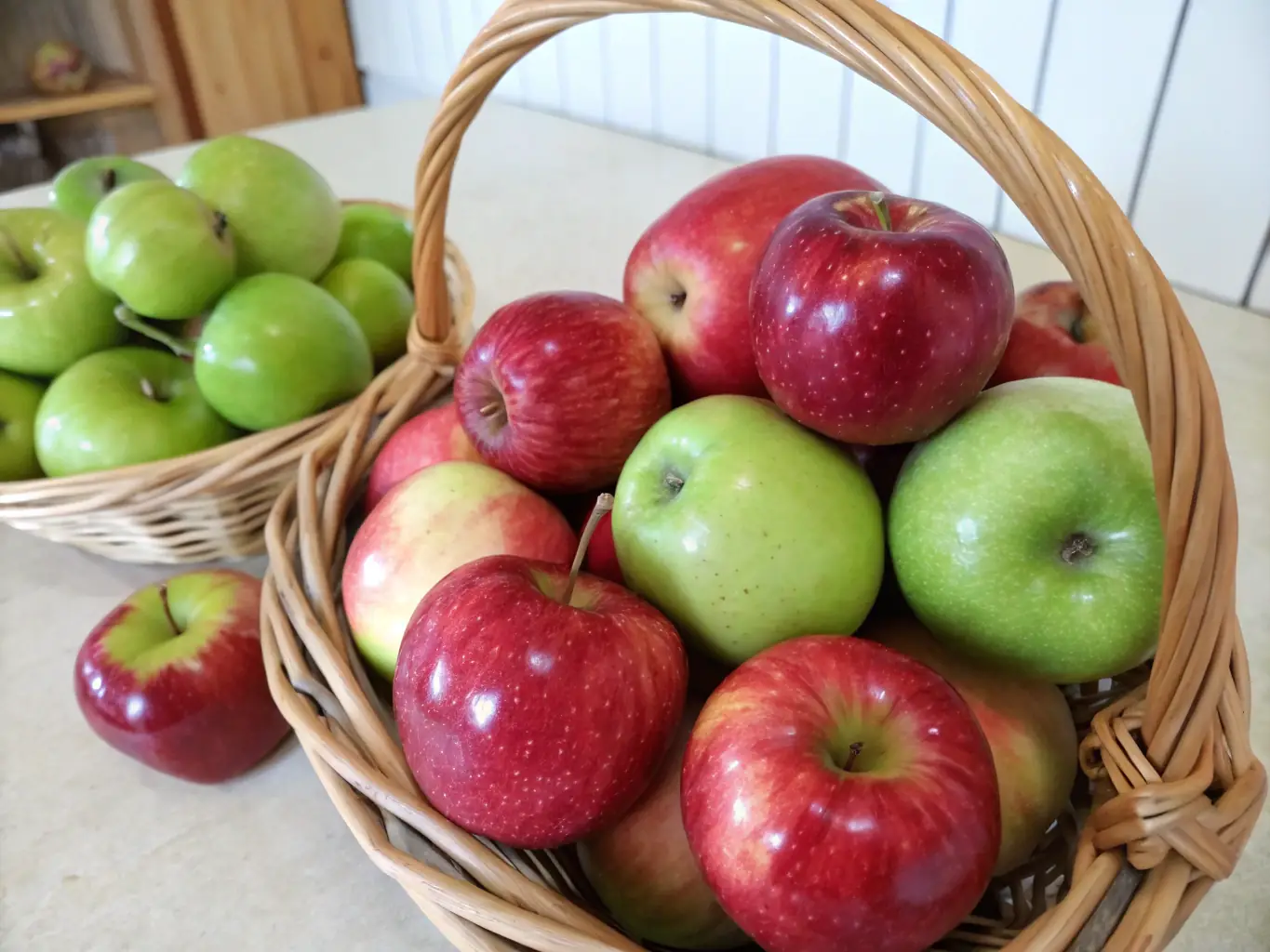 A close-up shot of a basket filled with shiny, red 'Honeycrisp' apples in an orchard setting, sunlight dappling through the trees.